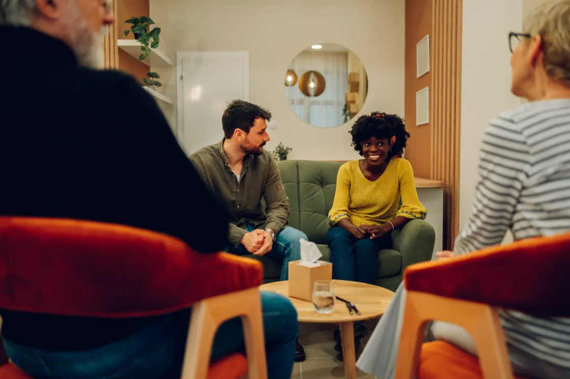 Two adults talking with a facilitator during a group therapy session at Ethos Wellness