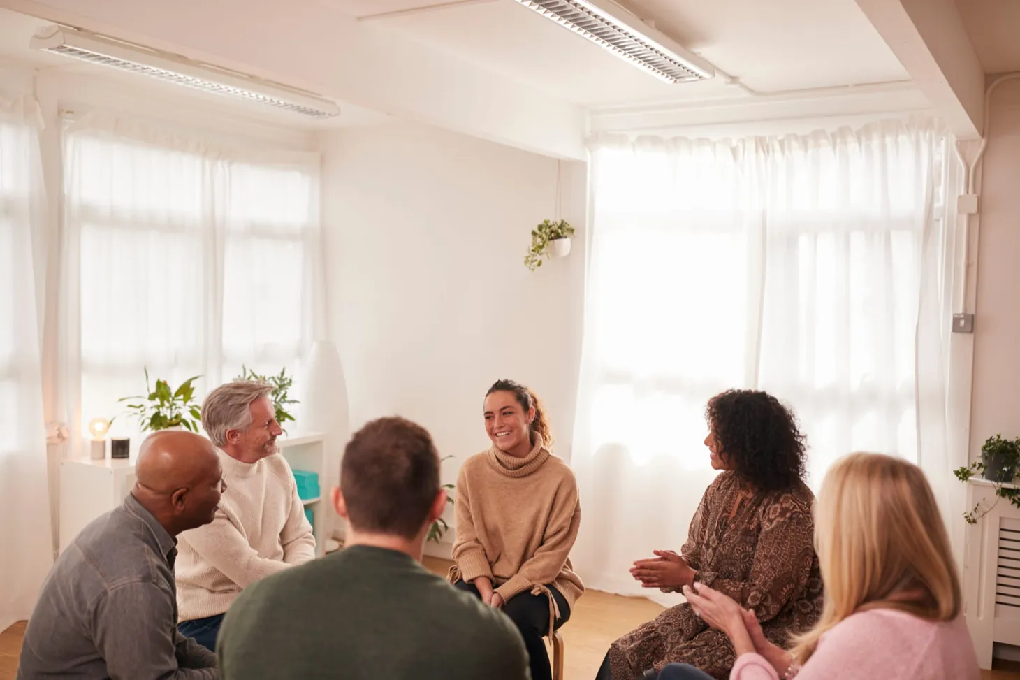Adults sitting together in a group therapy session at Ethos Wellness