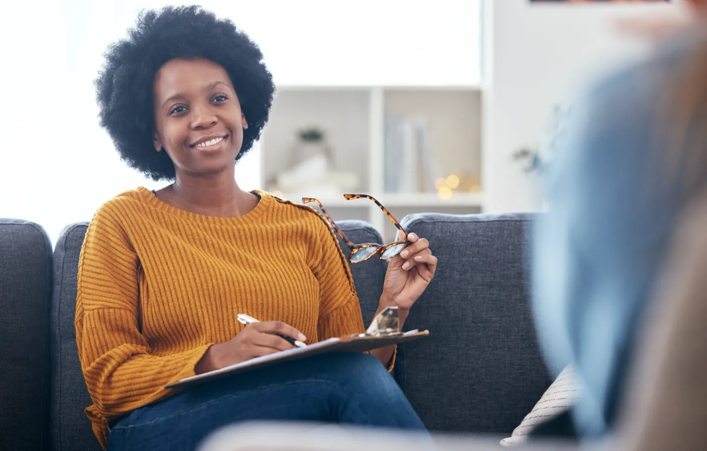 Smiling therapist with a notepad during an adult therapy session at Ethos Wellness